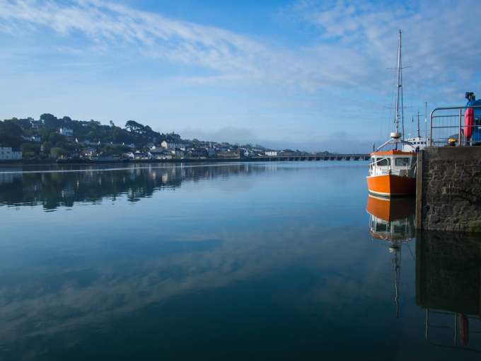 Orange boat reflecting in the calm River Torridge at Bideford in North Devon 