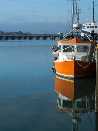 Orange boat reflecting in the calm River Torridge at Bideford in North Devon 
