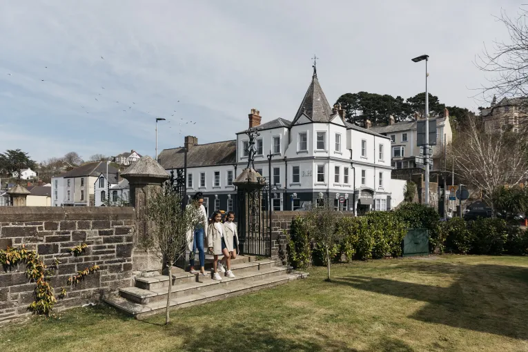 A mother and her children walking through the park gates with the Royal Hotel Bideford in the background