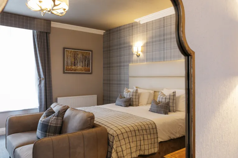 A King-size bed and sofa seen reflected in a mirror in one of the bedrooms at The Royal Hotel Bideford