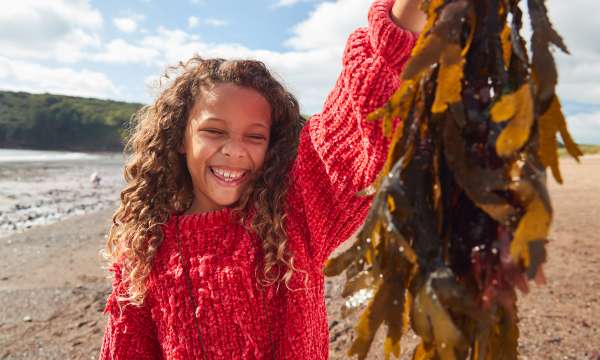 Girl holding seaweed wearing red jumper