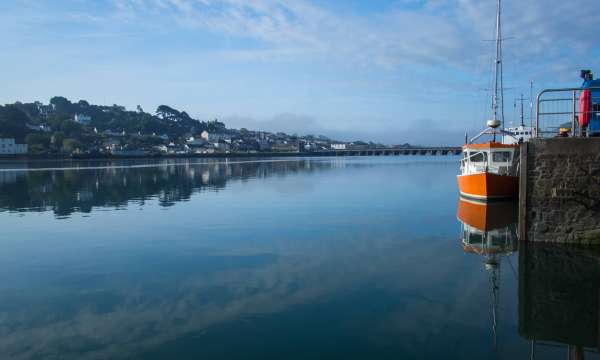 Orange boat reflecting in the calm River Torridge at Bideford in North Devon