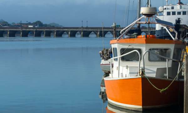 Orange boat reflecting in the calm River Torridge at Bideford in North Devon