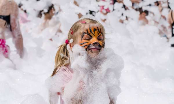 Girl with tiger face painting in foam party