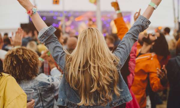 Young woman with blonde hair is dancing with her friends at a music festival