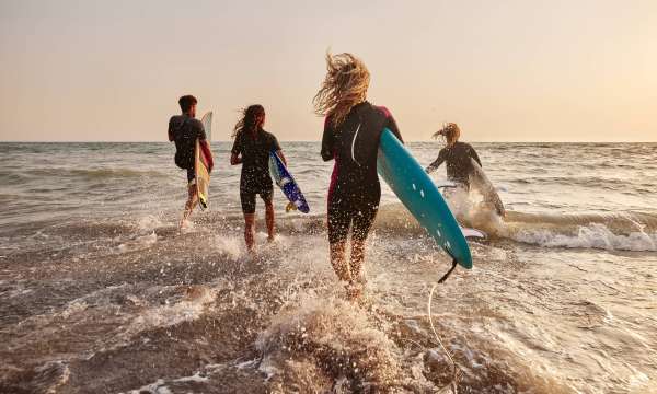 Group of surfers running into the water