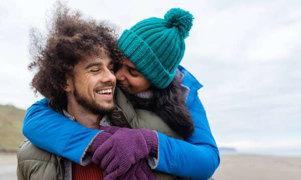 A couple enjoying walking along the coast together. It's cold outside so they are wrapped up warm.