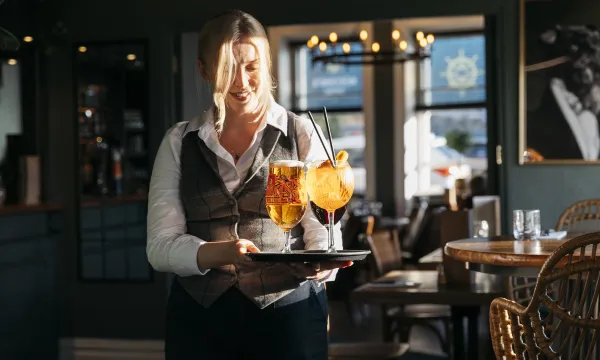 Waitress carrying a tray of drinks to a table