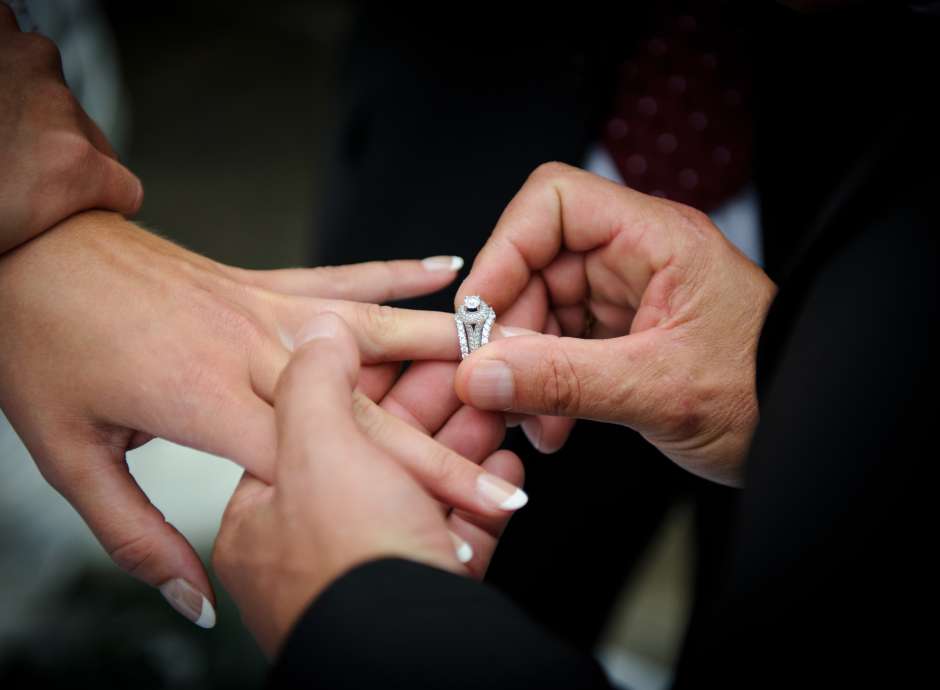 groom putting wedding ring on finger of bride