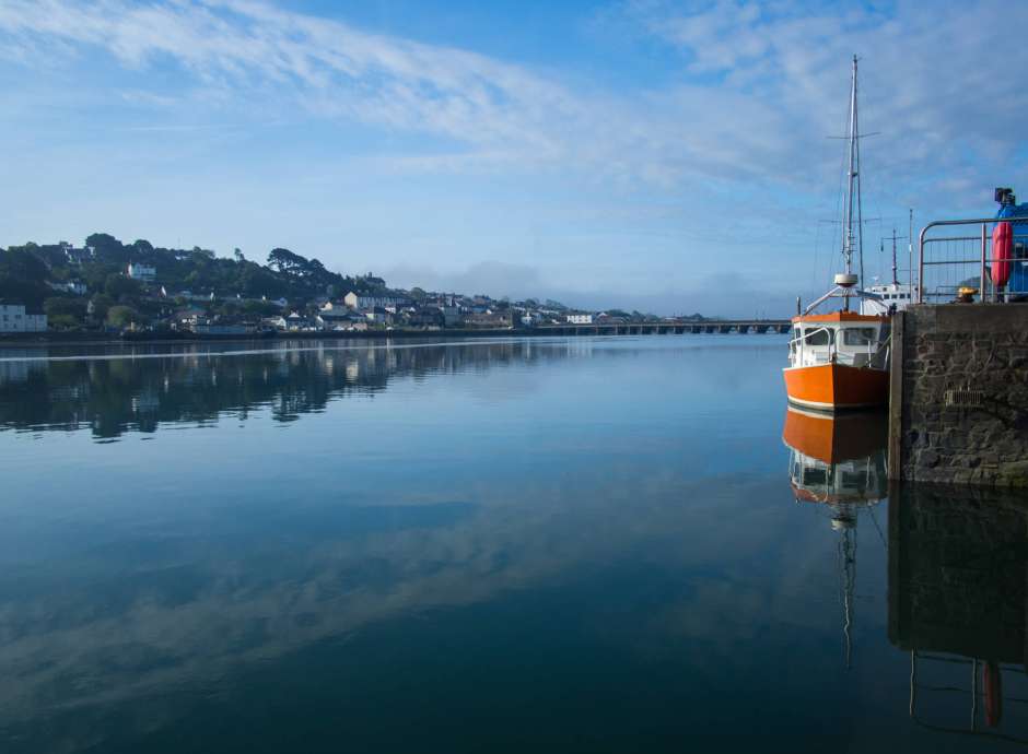 Orange boat reflecting in the calm River Torridge at Bideford in North Devon