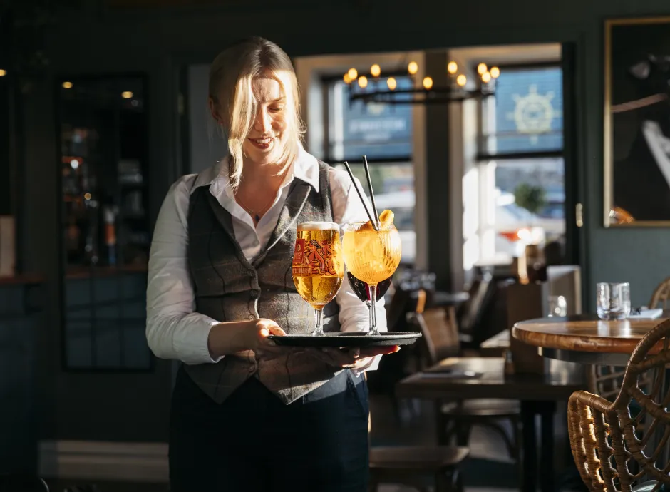 Waitress carrying a tray of drinks to a table