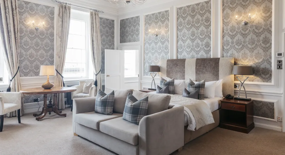 A large bedroom suite inside The Royal Hotel Bideford with a King-size bed, sofa and seating area
