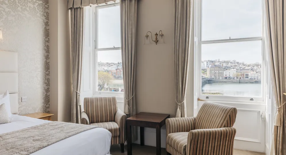 A seating area in a guest bedroom inside The Royal Hotel Bideford with views from the window over the river