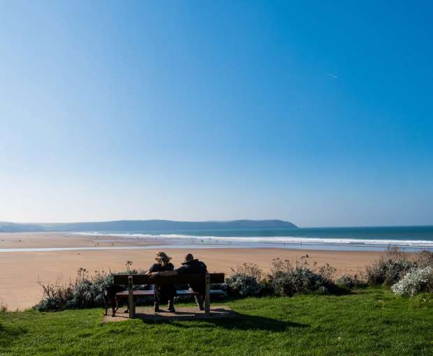 Couple Sitting on Bench Overlooking Woolacombe Beach North Devon